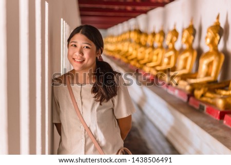 Cute Asian teen smile happy travel in temple with buddha row background