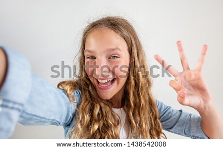 Smiling teen making selfie photo on smartphone over white background happy girl