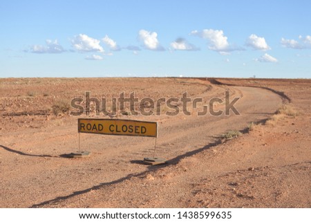 Road closed sign in the outback land of the red center of Australia somewhere between South Australia state and the Northern Territory federal northern regions of Australia. No people. Copy space