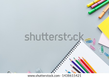 School supplies stationery, colour pencils, clips, paper on gray background, back to school concept with copy space for text, overhead, modern elementary education. flat lay, top view, mockup