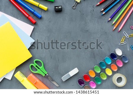 School supplies stationery, colour pencils, paints, paper on gray concrete background, back to school concept with copy space for text, modern elementary education. flat lay, top view, mockup