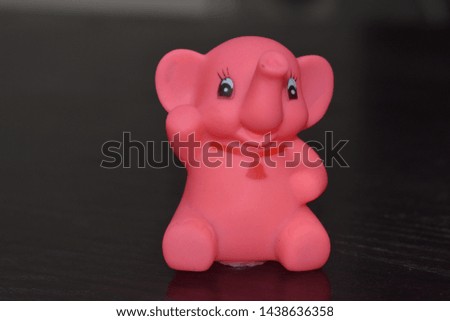 Rose color baby elephant toy closeup in black background 