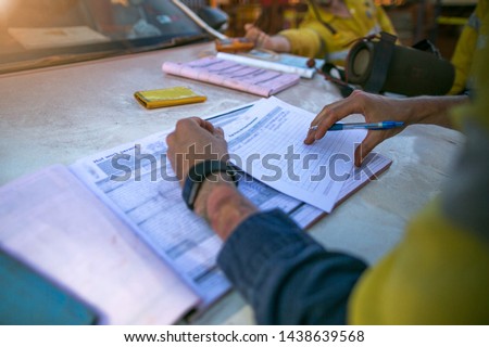 Construction coal miner supervisor conducting safety checking on job hazards analysis on hot work permit before sign off approval to work on  open field construction coal mine site Sydney, Australia 