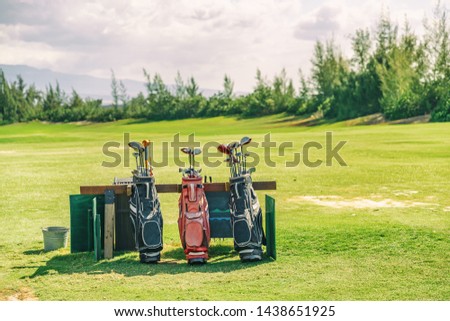 Golfing bags with clubs on golf course green grass background.