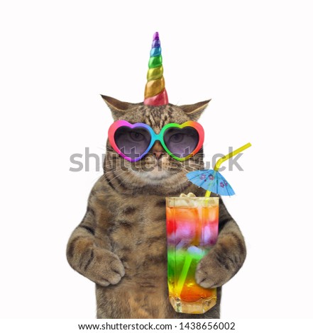 The cat unicorn in sunglasses is holding a glass of colored cocktail with a straw. White background. Isolated.