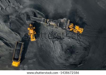 Open pit mine, excavator loads coal to crushing machine, chopper and sorting, top view aerial drone.