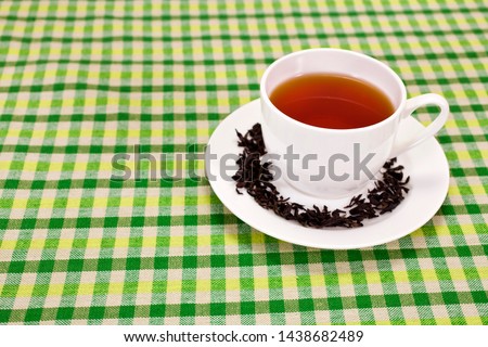 Black tea in a white cup on textile background. Copy space.