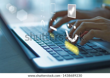 Businesswoman pressing face emoticon on the keyboard laptop .Customer service evaluation concept. Blue tone Royalty-Free Stock Photo #1438689230