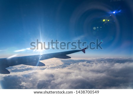 Up in the air, view of aircraft wing silhouette in dark blue sky horizon and cloud background in sunset time. viewed from airplane window, with a reflection camera lens Royalty-Free Stock Photo #1438700549