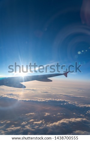Up in the air, view of aircraft wing silhouette in dark blue sky horizon and cloud background in sunset time. viewed from airplane window, with a reflection camera lens Royalty-Free Stock Photo #1438700555