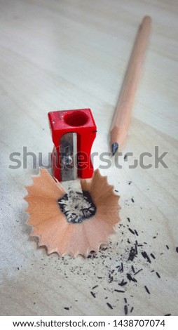 Pencil and sharpener, isolated on wood background.