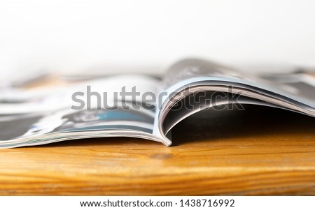 Magazine on wooden table. Beauty or fashion tips and trends. Open page with news article, column or celebrity interview. Media publication.  Royalty-Free Stock Photo #1438716992