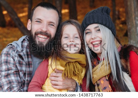 Outdoor family leisure. Joyful young parents enjoying time with their daughter in forest. Foliage background.