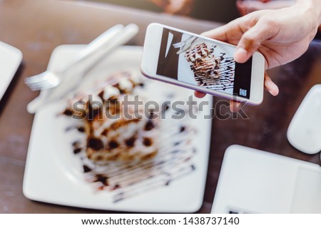 Young woman taking a photo of her 
Dessert with her smartphone. 