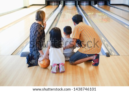 Rear view asian family playing bowling together