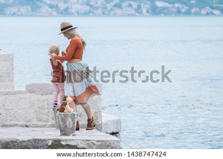 The family stands on the beach with a little girl