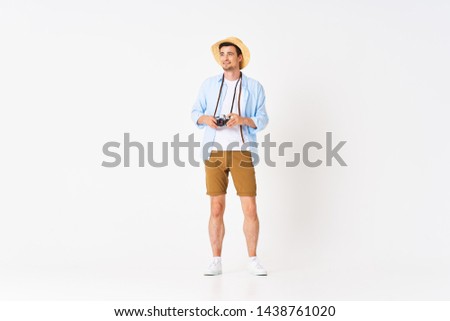 a guy in short shorts and a shirt with a hat on his head and a camera around his neck