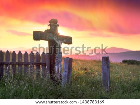 wooden cross in the Carpathians after a thunderstorm with lightning and thunder over the tops of the ridges, with strong wind and rain - there comes a clear beautiful morning