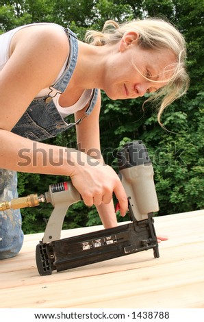 An attractive girl shows off her handywoman skills by nailing on new cedar decking.