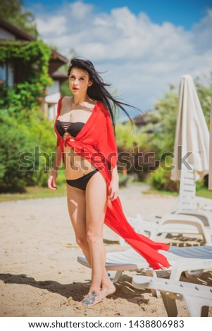 Vacation time. Woman in black swimsuit and red tunic at summer days