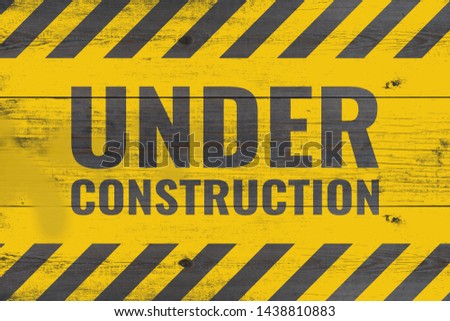 under construction warning message painted on aged wooden planks