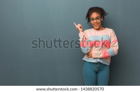 Young african american girl with blue eyes pointing to the side with finger