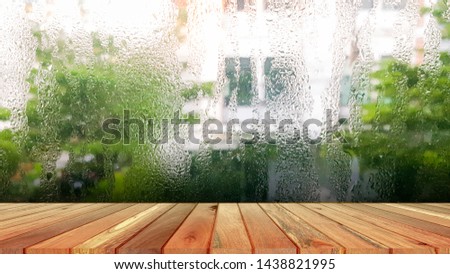Wood plank with abstract water drop on glass background of glass window shop on a rainy day. Free place for creativity. Background.