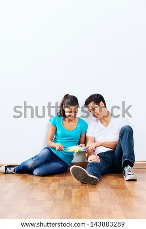 couple choosing perfect colour for their new home together sitting on wooden floor