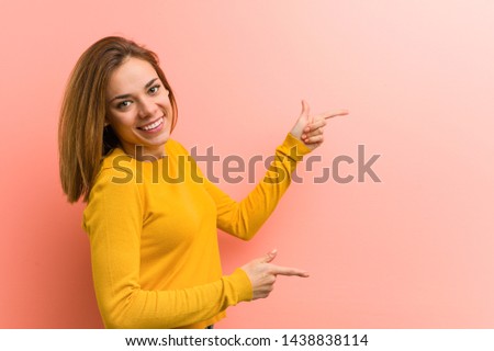 Young pretty young woman excited pointing with forefingers away.
