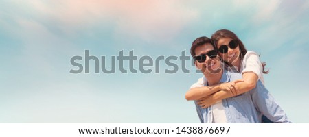 Happy Young couple wear sunglasses having fun on blue sky and the beach. Copy space. Piggyback ride. Web banner, panoramic.