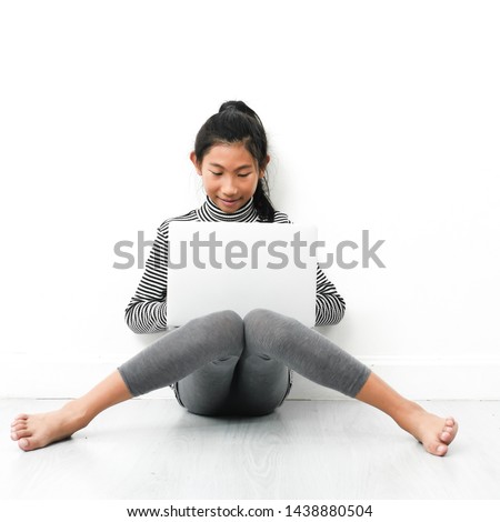 Asian girl sitting on floor and using laptop at home.