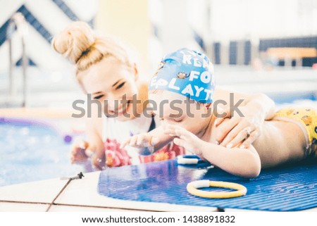Little boy with his mother learning surfing and having fun in swimming pool.