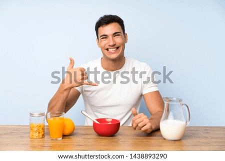 Handsome man in having breakfast making phone gesture