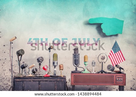 Retro old microphones, USA flag, big pointing finger front aged grunge concrete wall background with 4th of July date text. Independence day congratulations greeting card. Vintage style filtered photo