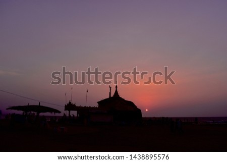 Silhouette image  of famous Chaungtha Pagoda at beach with pink and magenta colored sunset