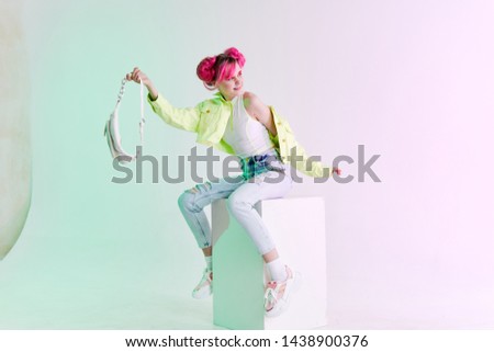 woman with pink hair sits on a white cube bag