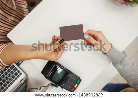 Closeup of customer in the store giving credit card to seller.