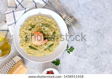 Italian risotto with spring asparagus and chrimps in plate on light background. Top view with copy space.