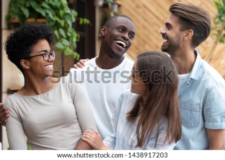 Portrait of overjoyed multiethnic young people stand embracing posing for picture together, happy diverse millennial friends or mates laugh feel excited meeting gathering in café. Friendship concept