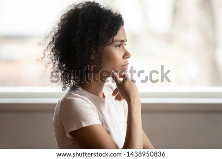 Pensive mixed race 30s woman sitting at home touch chin lost on deep thoughts thinking makes decision, side view face, challenge, problems solution, solving issues, consideration or brain work concept Royalty-Free Stock Photo #1438950836