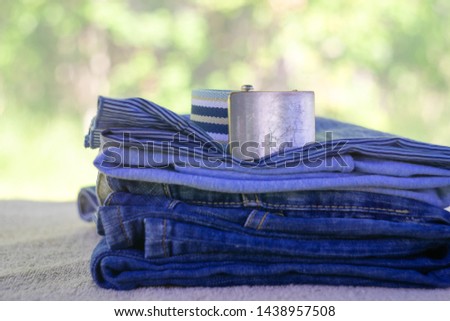 Denim blue jeans stack on a blurred natural background. Accessory belt denim.