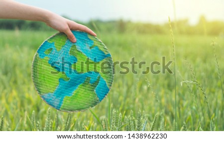 Teen girl holding planet in hands against green spring background. Earth day holiday concept. Protection and love of earth