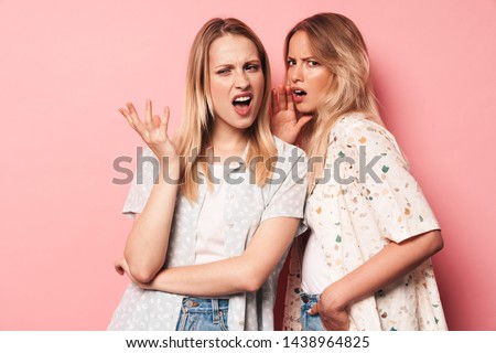 Photo of displeased confused pretty blondes women friends posing isolated over pink wall background talking with each other. Royalty-Free Stock Photo #1438964825