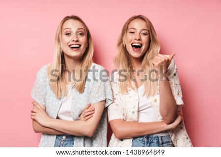 Picture of happy smiling pretty blondes women friends posing isolated over pink wall background showing thumbs up gesture. Royalty-Free Stock Photo #1438964849