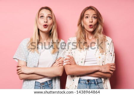 Photo of surprised shocked pretty blondes women friends posing isolated over pink wall background. Looking aside.
