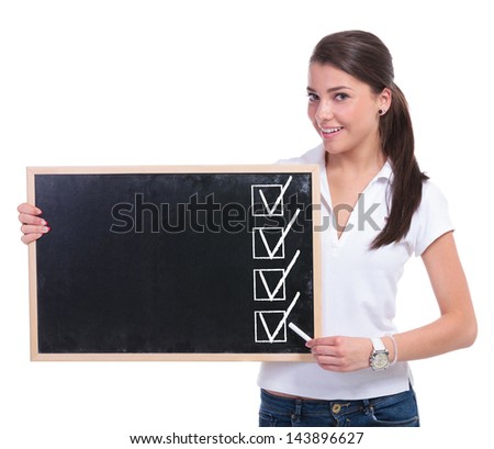 casual young woman holding a small blackboard and presenting four checked boxes on it with some chalk while smiling to the camera. isolated on white background