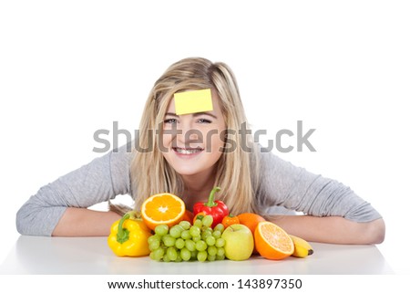 Smiling teenage girl with blank sticky note on forehead by fruits and vegetables