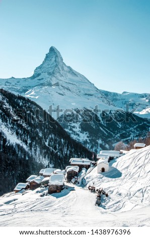 Zermatt siing slopes with the impressive Matterhorn  in the background on a perfect Winter day with a blue sky and the old alpine village Findeln in the foreground on a morning with fresh powder snow