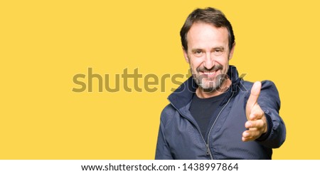 Middle age handsome man wearing a jacket smiling friendly offering handshake as greeting and welcoming. Successful business.