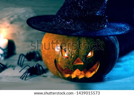 creepy pumpkin for Halloween in witch hat on wooden background
